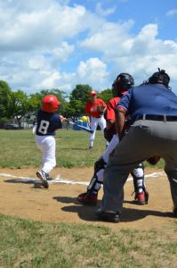 Softball game with young child striking ball with a bat at Skiddy Park