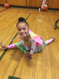 A girl dressed as a butterfly with in bright green neon tutu and multi-colored shirt, and bright colored butterfly wings.