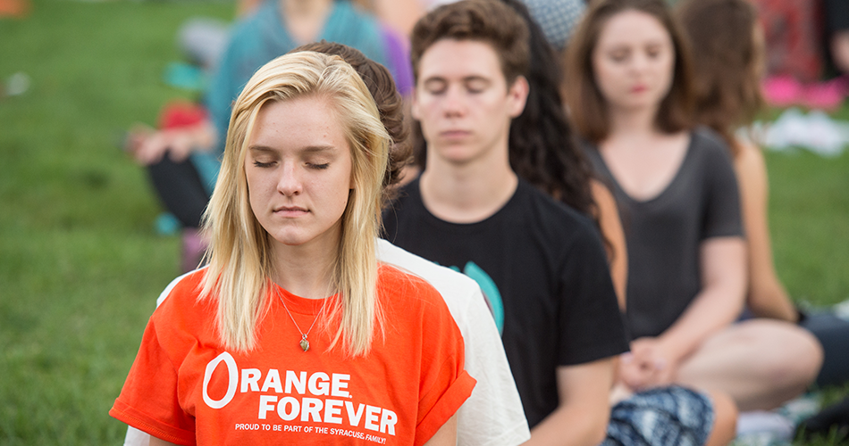 Students meditating in grass