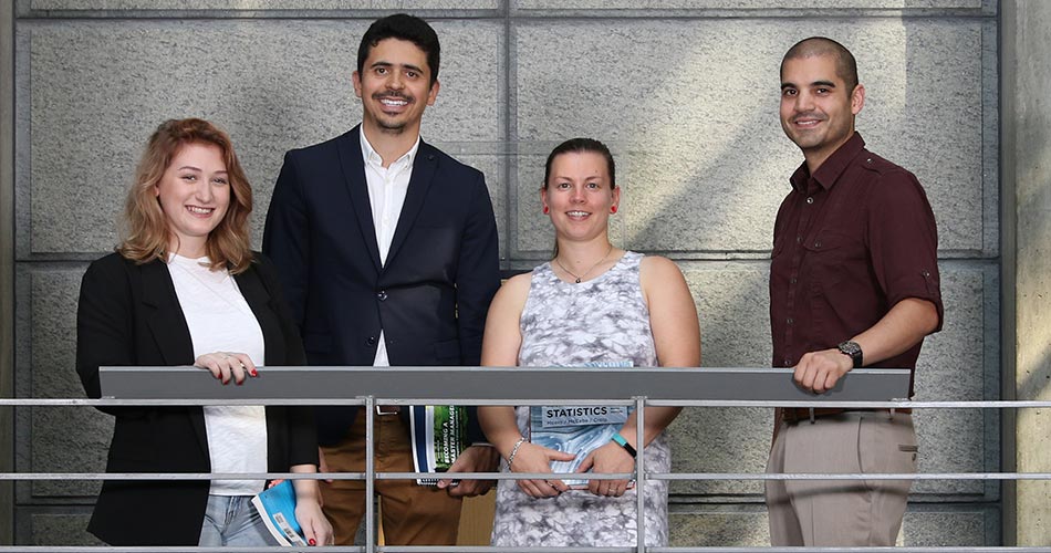 Four Maxwell students standing together by a railing