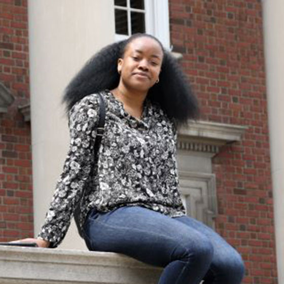 Student sitting in front of Maxwell Hall