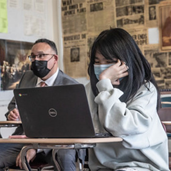 Masked student in class with a laptop