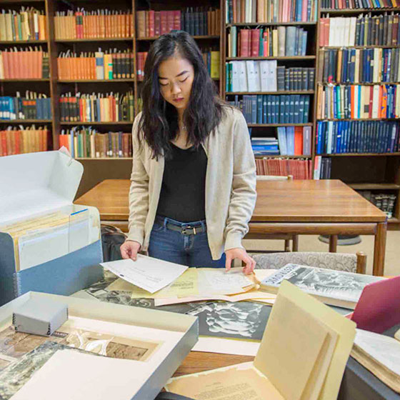 Student conducting research in a room with many books