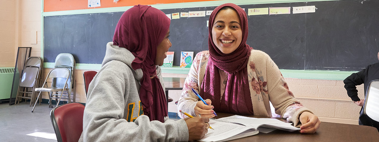 Female students at desk with book