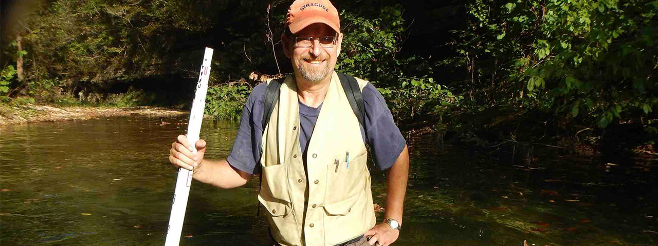 Man standing in creek with measurement pole