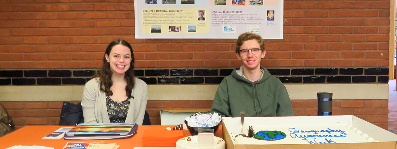 Students sitting at a table with a large cake