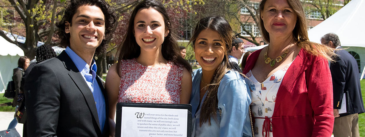 smiling Maxwell Graduates Pose with Oath Padfolio