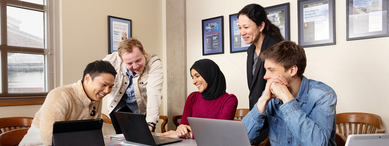 Group of people sitting at table looking at a computer