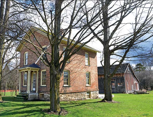 Brick house with a wooden barn behind it