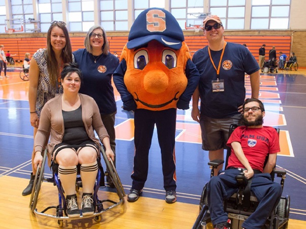 Three people standing and two in wheelchairs with Otto