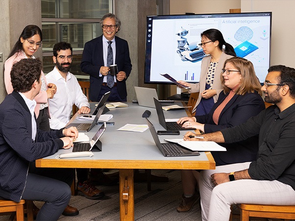 Group of people sitting at table in front of tv screen