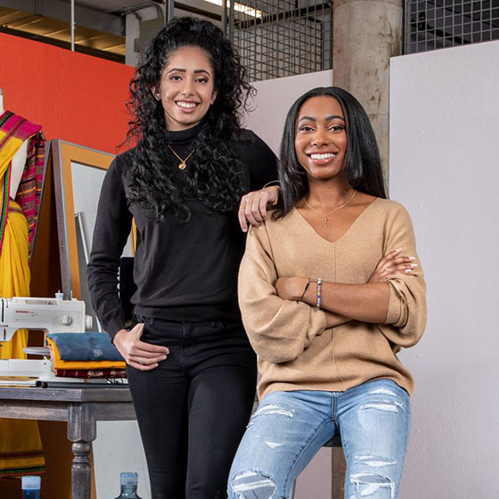 Maxwell Undergraduates Nikita Chatterjee (Economics) and Brianna Howard (Public Health) with sewing machine and cloth.